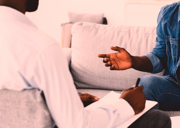 Two people engaged in a serious conversation on a couch.