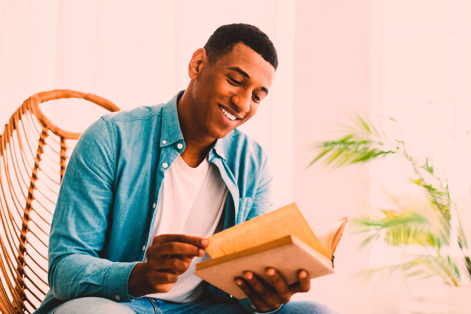 Young man smiling while reading a book indoors.